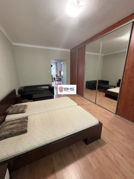 Bedroom with a double bed, mirrored wardrobe, and wooden decor flooring in a 2-room apartment.