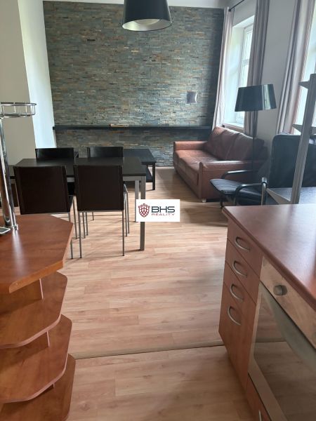 Interior of a 2-room apartment with a wooden decor floor and a stone wall in the living room.
