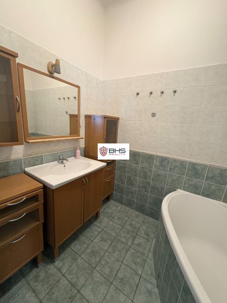 A bathroom in a 2-room apartment with a bathtub and a wooden cabinet.