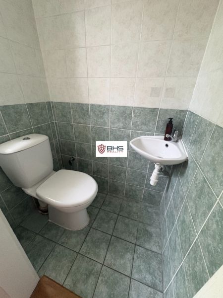 A toilet with tiles and a small sink in a 2-bedroom apartment.
