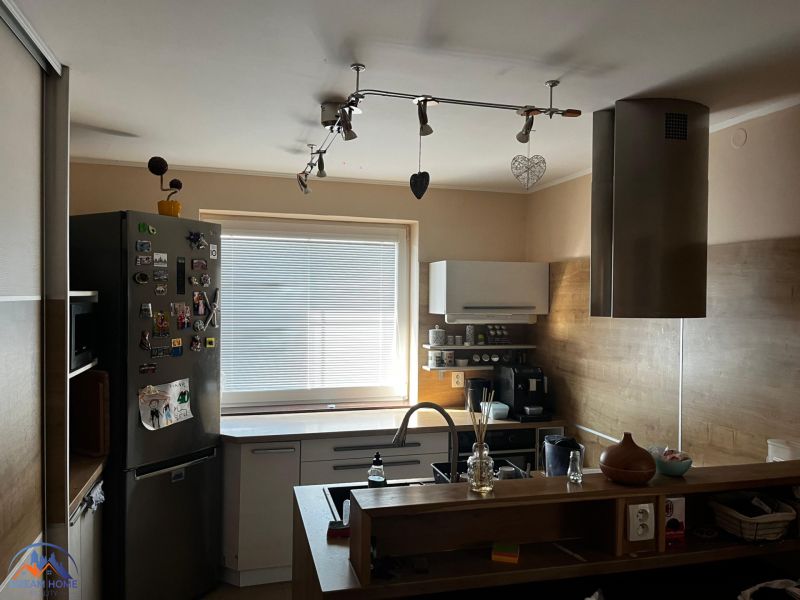 A kitchen in a family house with a metal range hood, floor with wooden decor.