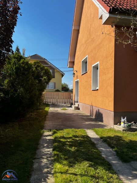 A family house in Čalovec with an orange facade, a lawn, and a paved driveway.