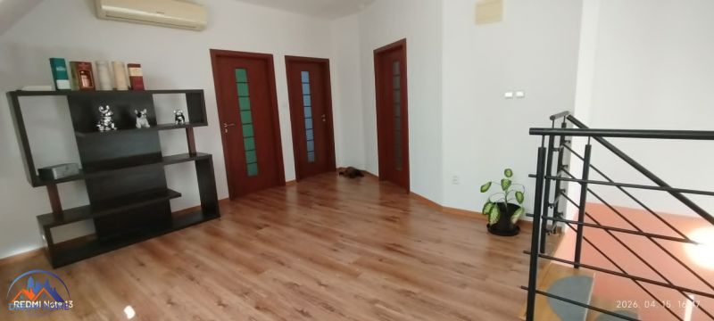 Interior of a family house with a wood-patterned floor, a shelf, and a plant.