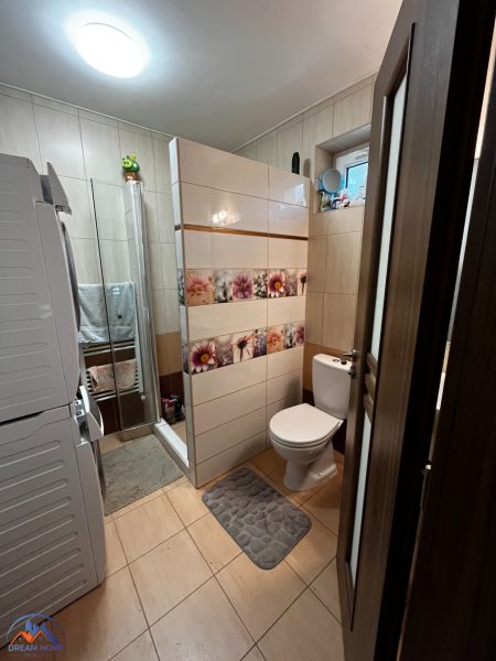 A bathroom in a family house with a washing machine, shower, and toilet.