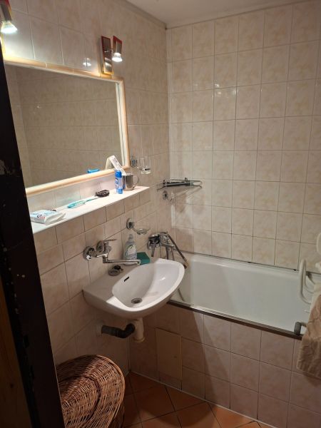 Bathroom with a bathtub, sink, and mirror in a 2-room apartment.