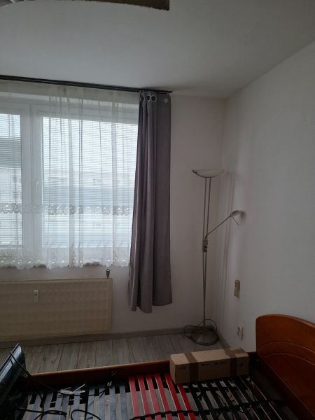 A room with a bed, windows, and a floor with wooden decor in a two-room apartment.