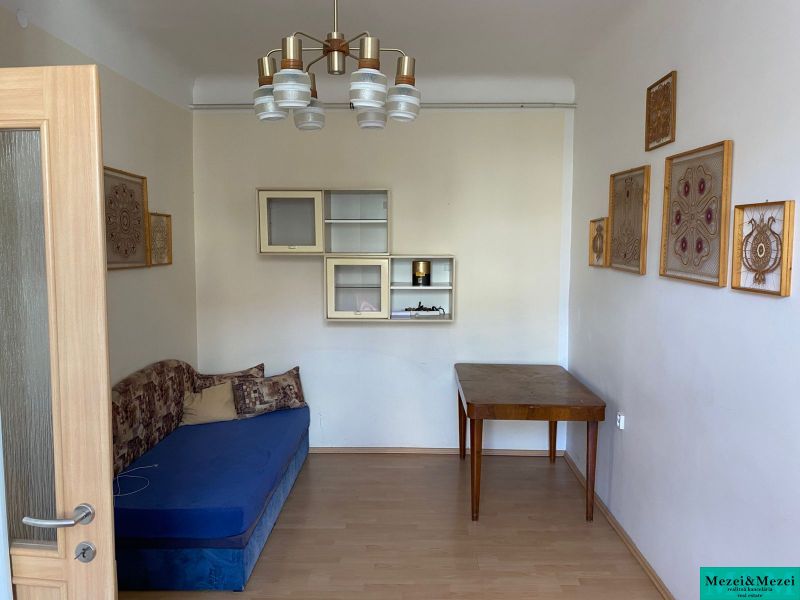 A room in a 2-room apartment with a blue sofa and a wooden table, floor with a wooden decor.