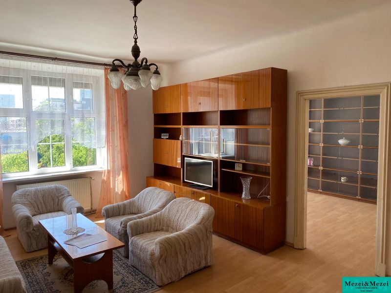 Living room of a two-room apartment with a wooden decor floor and comfortable seating.