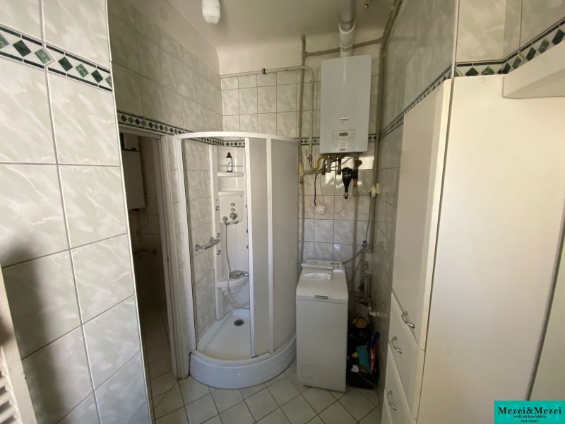 A bathroom with a corner shower and a washing machine in a 2-room apartment.