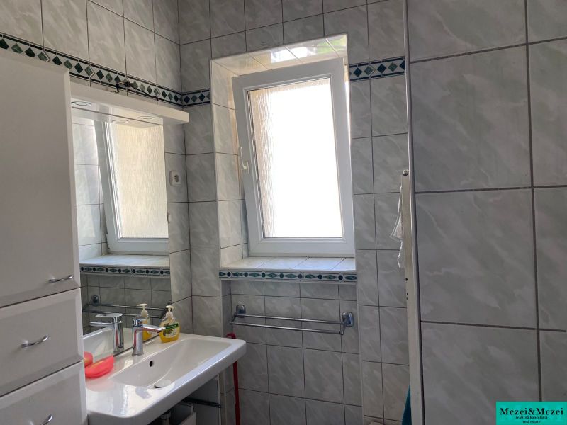 Bathroom in a 2-room apartment with tiles, a sink, and a window.