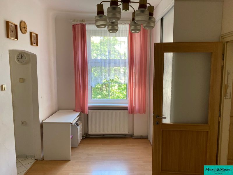A room with a wooden floor decor and pink curtains in a two-room apartment.