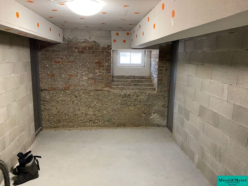 Basement room with concrete walls and a window in a two-room apartment.