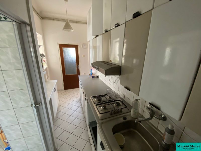 A kitchen in a 2-room apartment with white cabinets and tiled flooring.