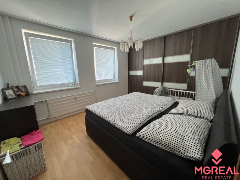 Bedroom in a 2-room apartment with a bed and a wardrobe, floor with wooden decor.