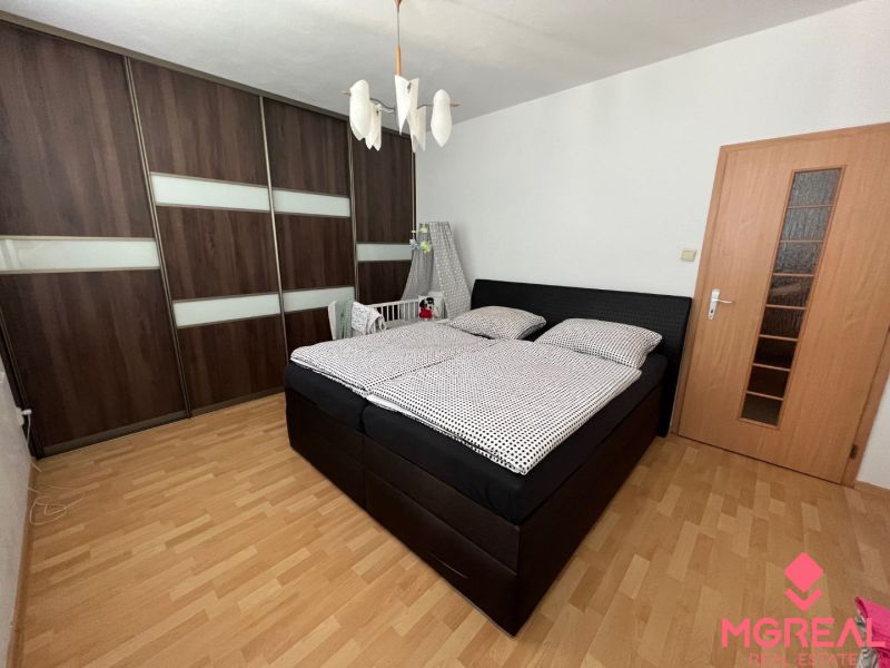 Bedroom in a 2-room apartment with a large wardrobe and a floor with a wooden decor.