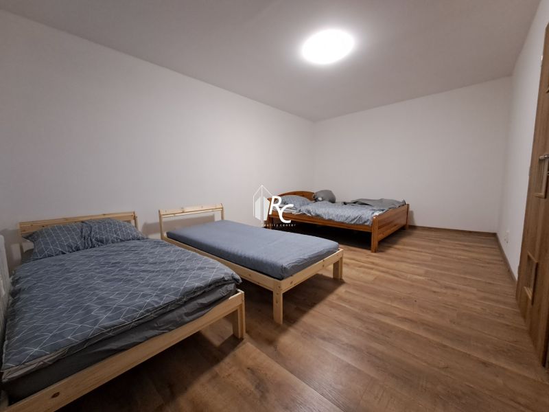 A bedroom with three beds and a wooden decor floor in a studio apartment.