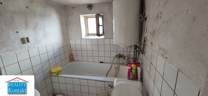 A bathroom in a family house with tiles, a bathtub, and a boiler.