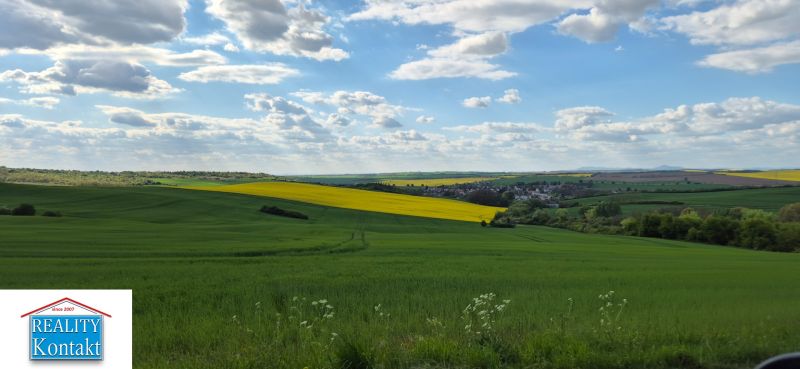 The village offers a breathtaking view of the green landscape with a blue sky and clouds.