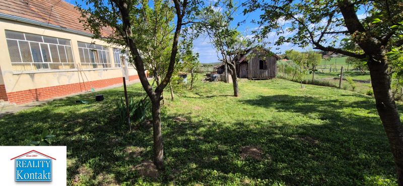 A family house in Dedinka with a glassed-in veranda, a garden, and a wooden structure in the yard.