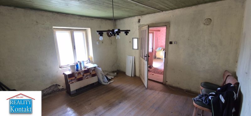 A room in a family house with a wooden decor floor, older furniture, and a window.