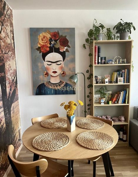 Dining room in a 2-room apartment with a painting, wooden table, and decorative accessories.