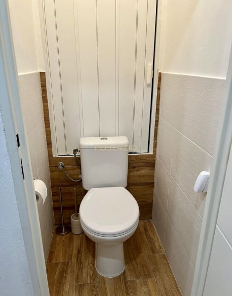 A bathroom in a 2-room apartment with a wooden decor floor.