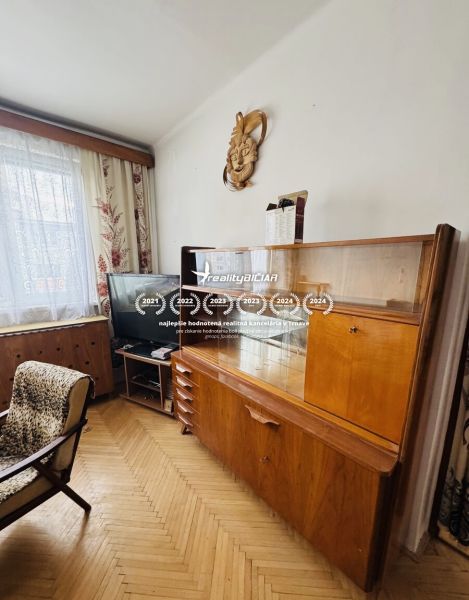 A view into a living room with retro furniture and a wooden decor floor in a 3-room apartment.
