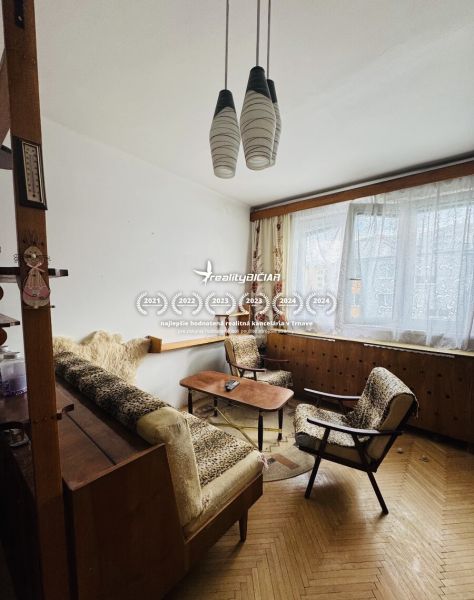 Living room in a three-room apartment with a wooden decor floor, retro furniture, and curtains.