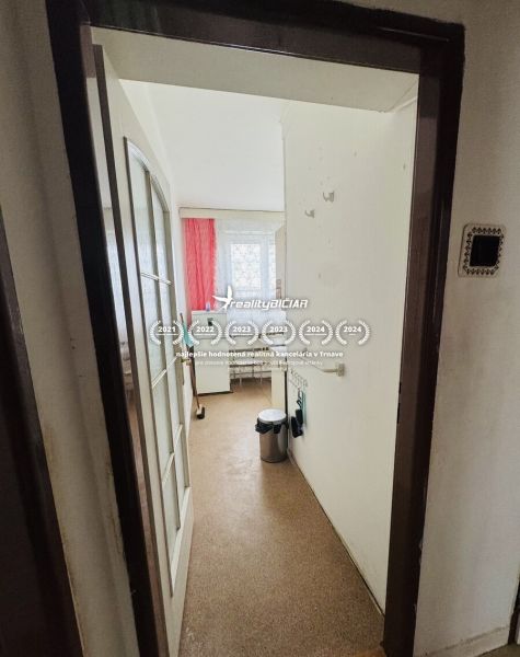 A narrow hallway leads to the kitchen in a 3-room apartment with red curtains.
