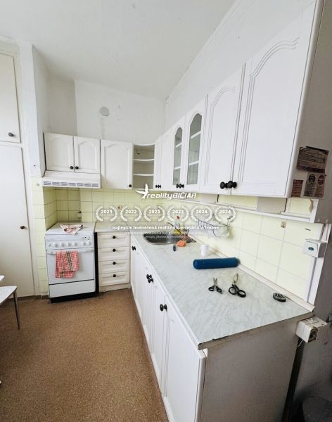 A kitchen with white cabinets and a stove in a 3-room apartment.