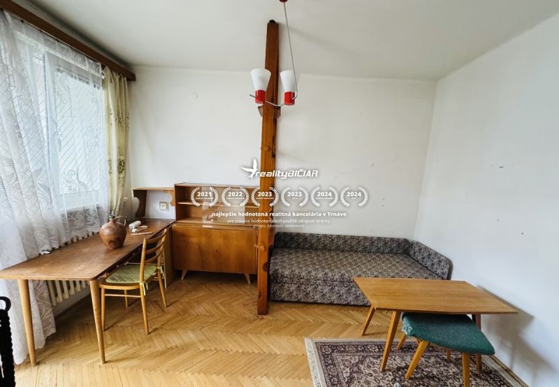 A room in a 3-bedroom apartment with a wood-patterned floor, furniture, and decorative accessories.