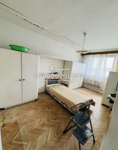 A room with a bed, a wardrobe, and a floor with a wooden decor in a 3-room apartment.