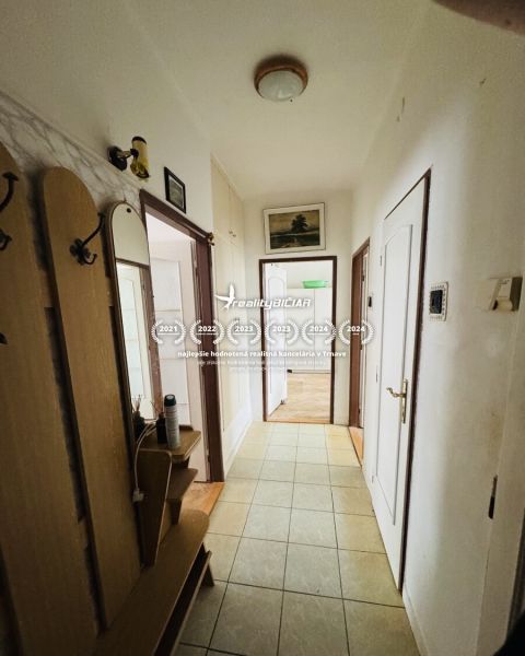A hallway of a 3-room apartment with entrances to other rooms and tiled flooring.