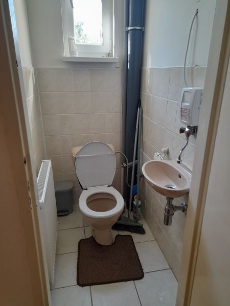A bathroom in a 4-room apartment with a sink, toilet, and window.