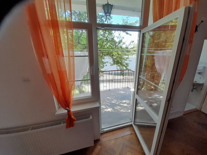 Open balcony with a view and orange curtains, floor with wooden decor.