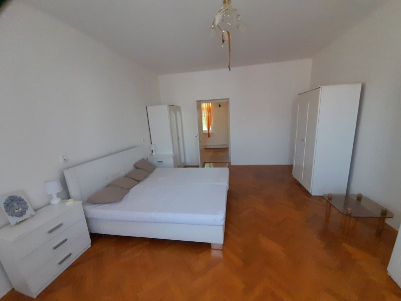 A bedroom in a 4-room apartment with light furniture and a wooden decor floor.