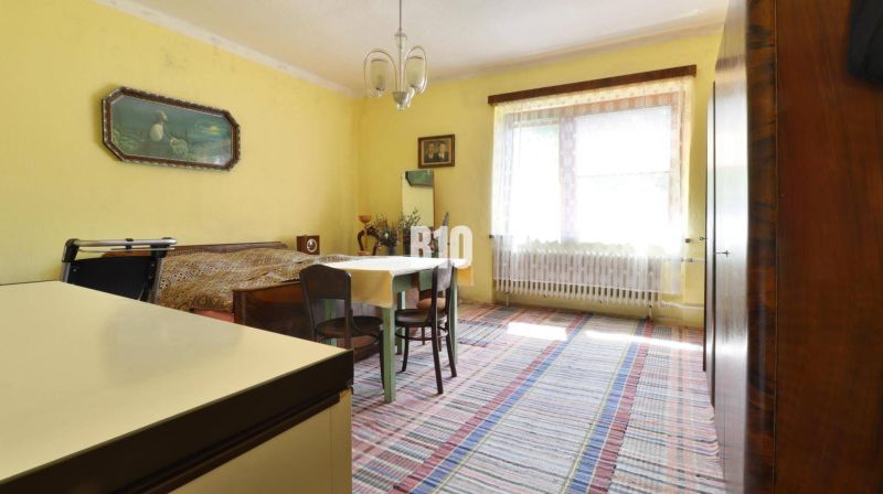 A room in a family house with yellow walls, a table, and a bed.