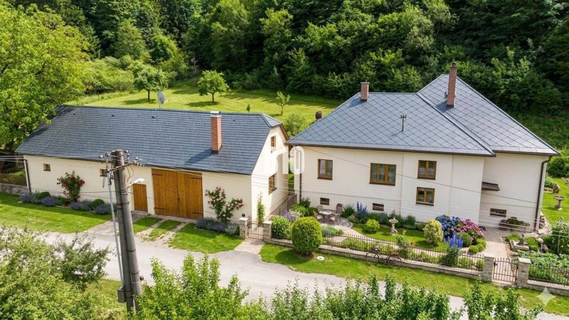A family house in Belá-Dulice with a landscaped garden and surrounding greenery.
