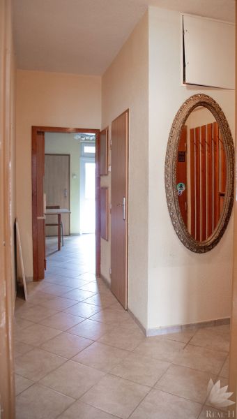 A hallway in a 2-room apartment with a large mirror on the wall and tiles.