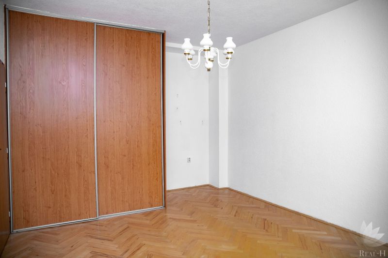 A room in a 2-room apartment with a wooden decor floor and a built-in wardrobe.