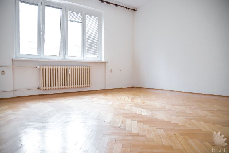 A room in a 2-room apartment with a large window and a floor with a wooden decor.