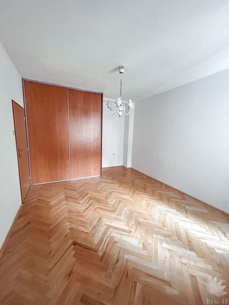 A room in a 2-room apartment with a wooden decor floor and a built-in wardrobe.