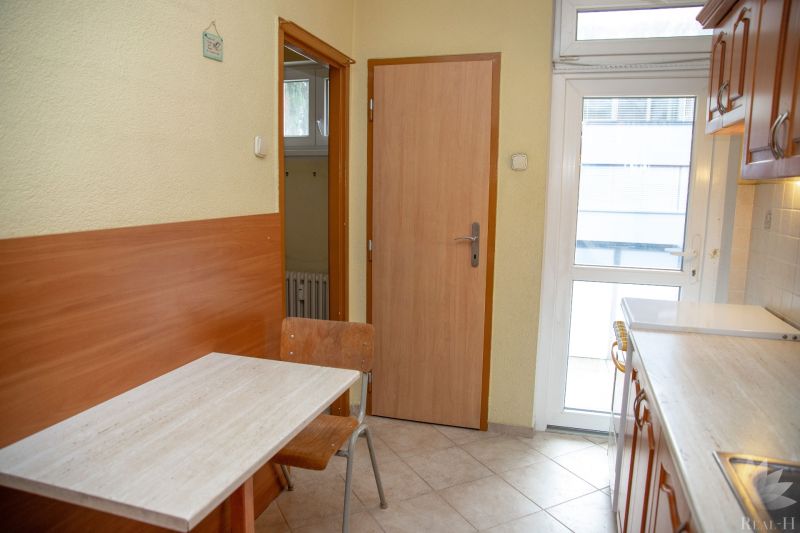 Kitchen in a 2-room apartment with wooden decor and a dining table and chairs.