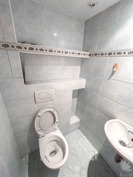 Bathroom with a toilet in a 2-room apartment, tiles with a simple pattern and a small sink.
