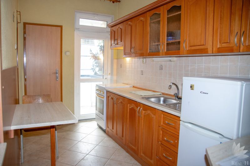 A kitchen with wooden cabinets and a table in a 2-room apartment.