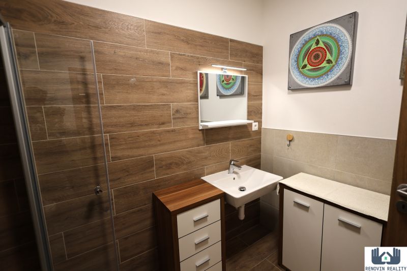 A bathroom with a wooden decor floor, a sink, and a mirror in a two-room apartment.