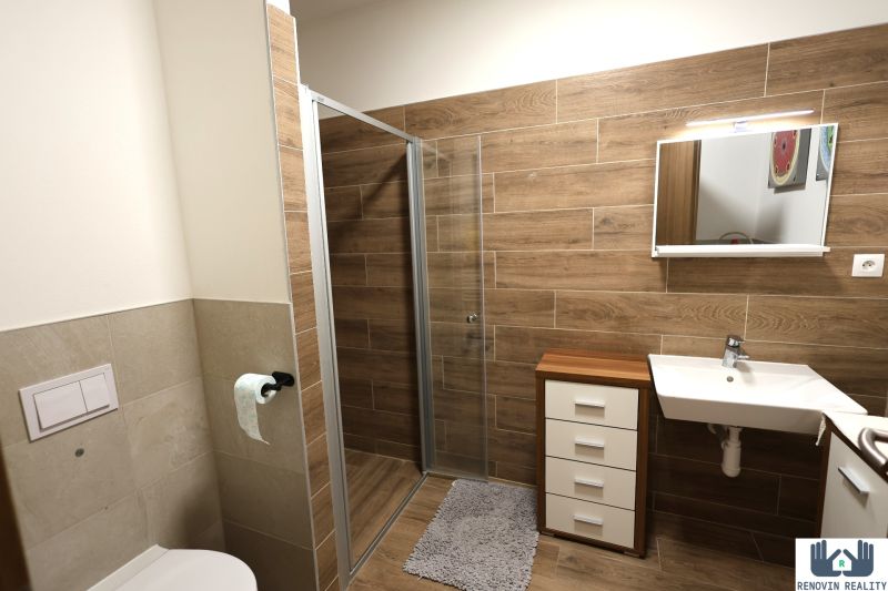 A bathroom in a 2-room apartment with a floor and walls with a wooden decor.