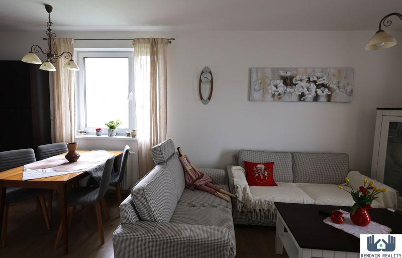 Living room of a two-room apartment with a sofa, table, decorations, and a floor with a wooden design.