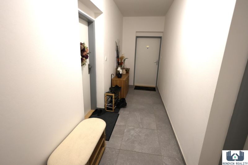 A hallway in a 2-room apartment with tiles, light-colored walls, and storage space.