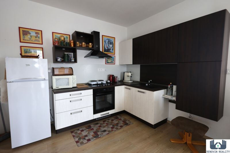 A kitchen unit in a 2-room apartment with decorative shelves and a floor with a wooden decor.